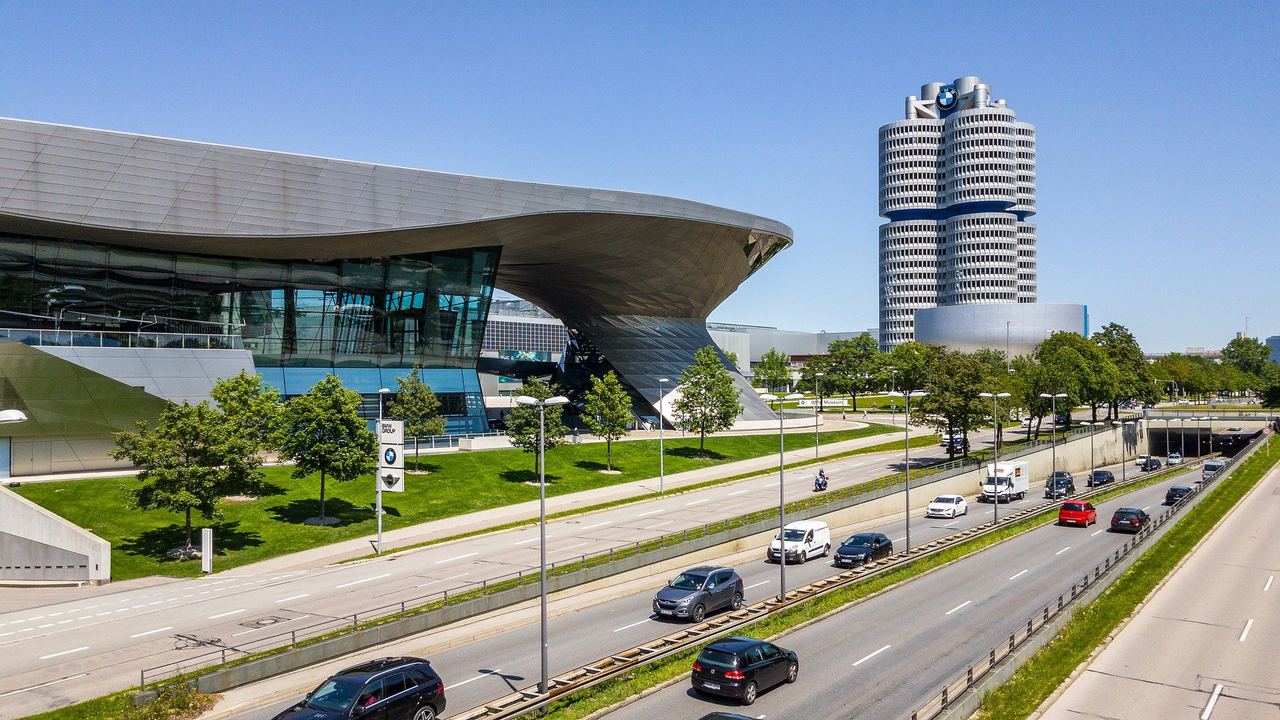 Modern corporate headquarters and showroom beside a busy multi-lane road in Munich on a sunny day