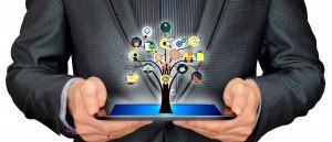Businessman holding a tablet with a tree of connected app icons growing from it