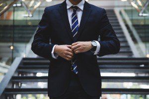 Businessman in a dark suit buttoning his jacket