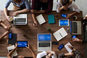 Overhead view of a team working together around a table with laptops and tablets