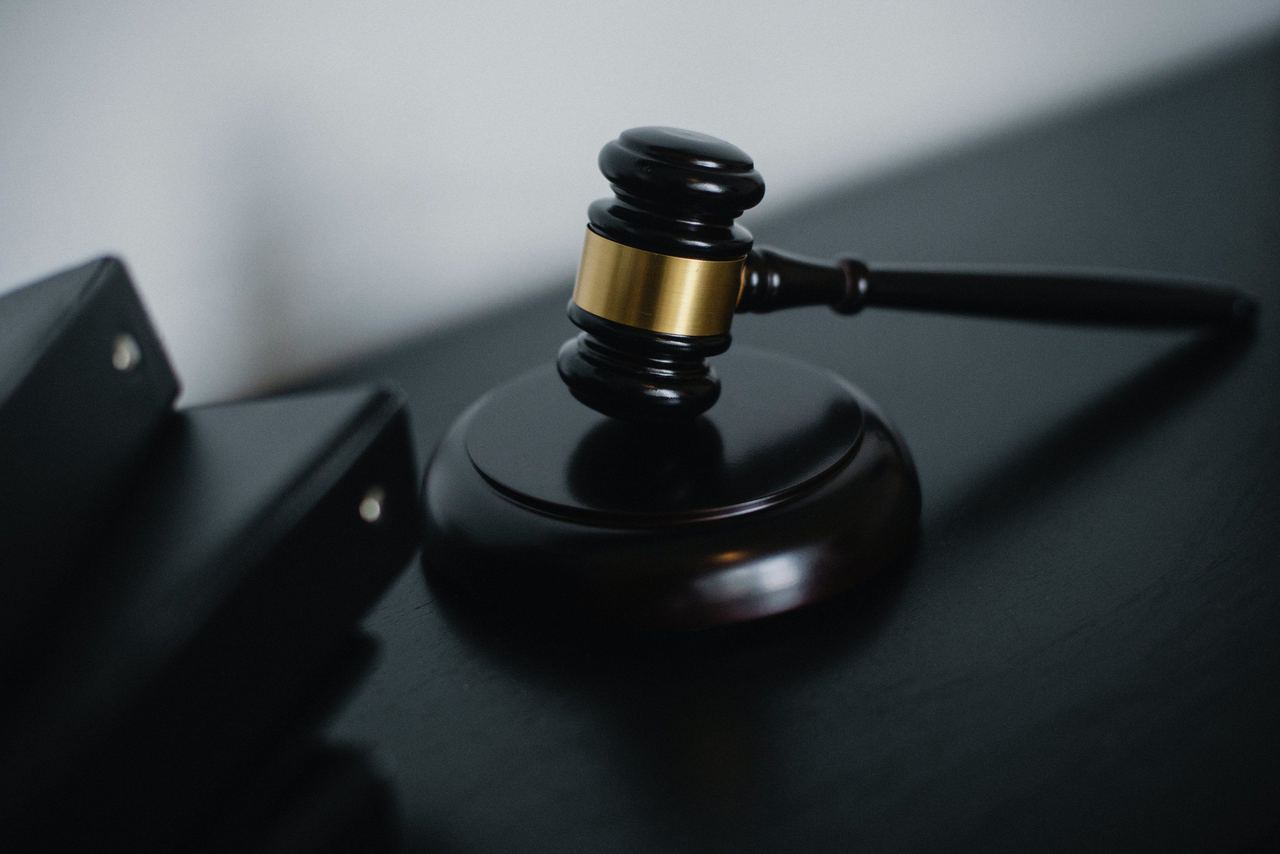 Judge’s gavel on a dark wooden desk beside black ring binders