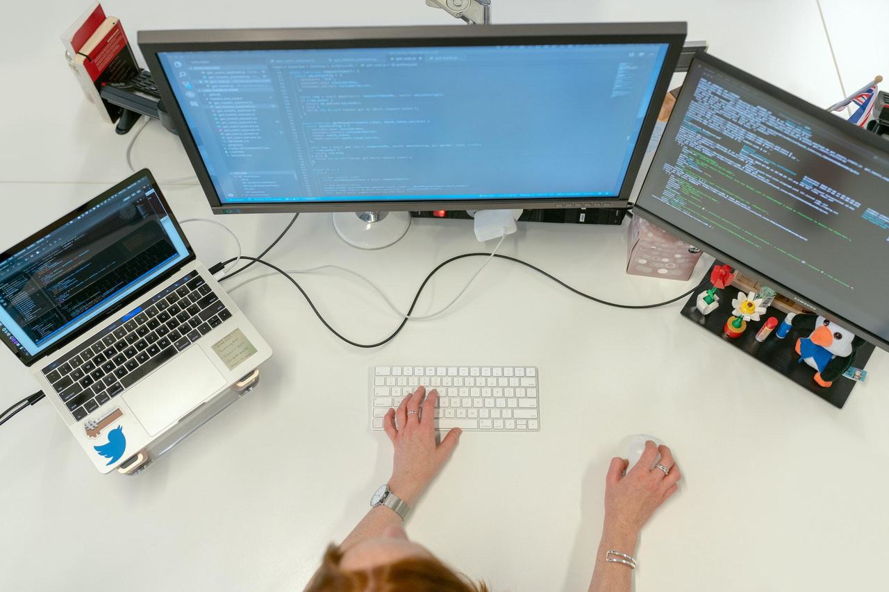 Desk with monitors, a laptop and a keyboard seen from above