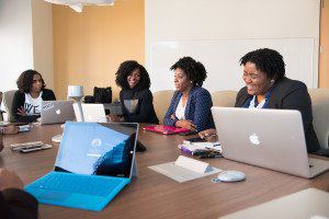 Colleagues talking around a meeting table with laptops