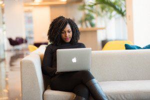 Woman working on a laptop while sitting on a sofa