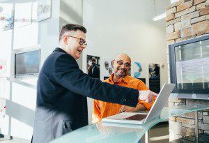 Two smiling colleagues looking at a laptop, one pointing at the screen