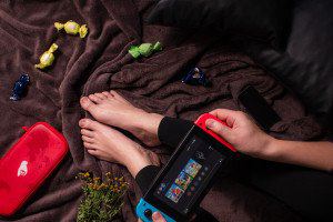 Person playing a handheld games console while relaxing on a blanket